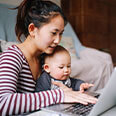 Mom wearing a striped shirt is browsing on a computer with her baby.